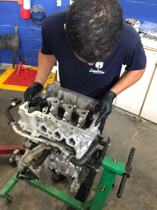 Mecânico inspecionando minuciosamente um bloco de motor desmontado no suporte