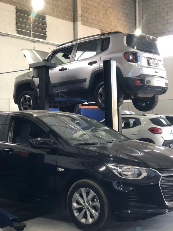 Jeep Renegade no elevador automotivo acima de um Chevrolet Onix, demonstrando capacidade de atendimento