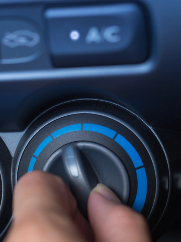 Dedo acionando o controle rotativo azul do ar-condicionado no painel do veículo
