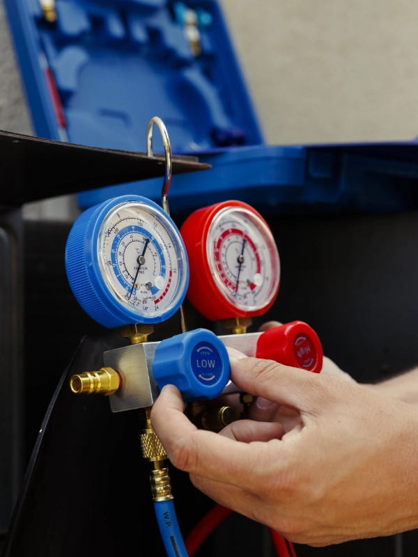 Mecânico ajustando manômetros vermelho e azul durante o teste de pressão do ar-condicionado