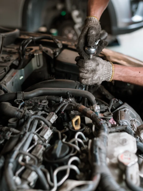 Mecânico com luvas sujas de óleo desmontando e inspecionando peças internas do motor