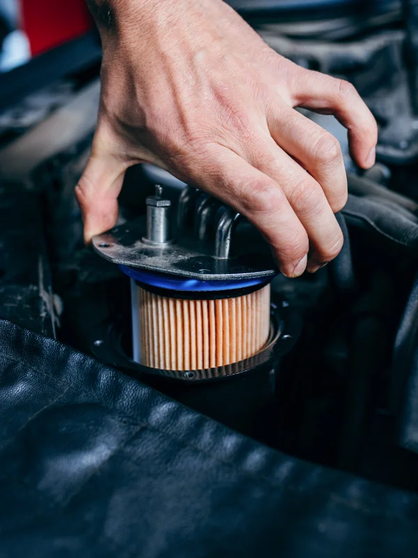 Mão de mecânico instalando cuidadosamente um novo filtro de óleo de papel no compartimento do motor